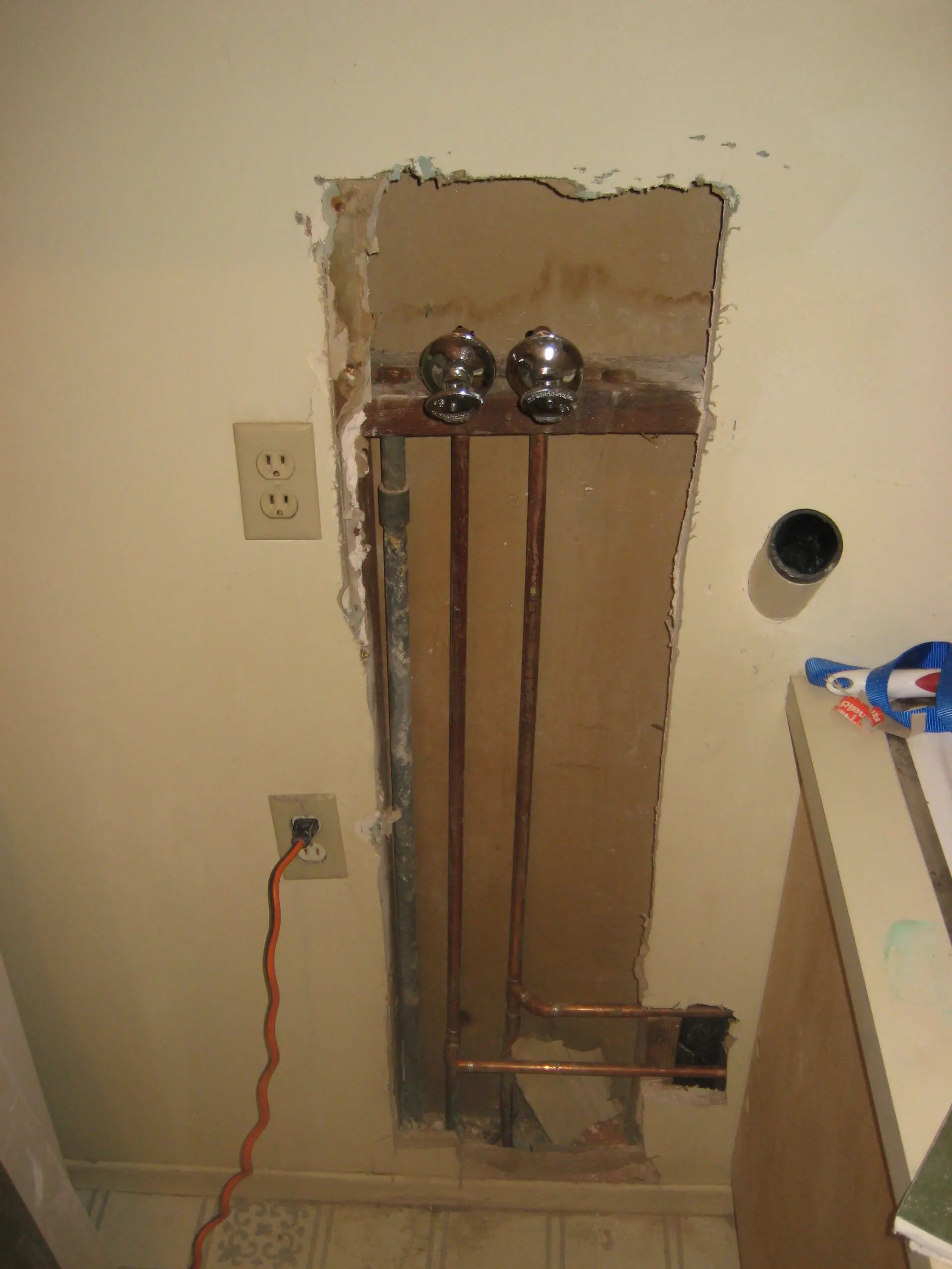 Damaged wall with exposed pipes